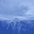 A mountainous landscape under a cloudy sky, depicted in monochrome blue.