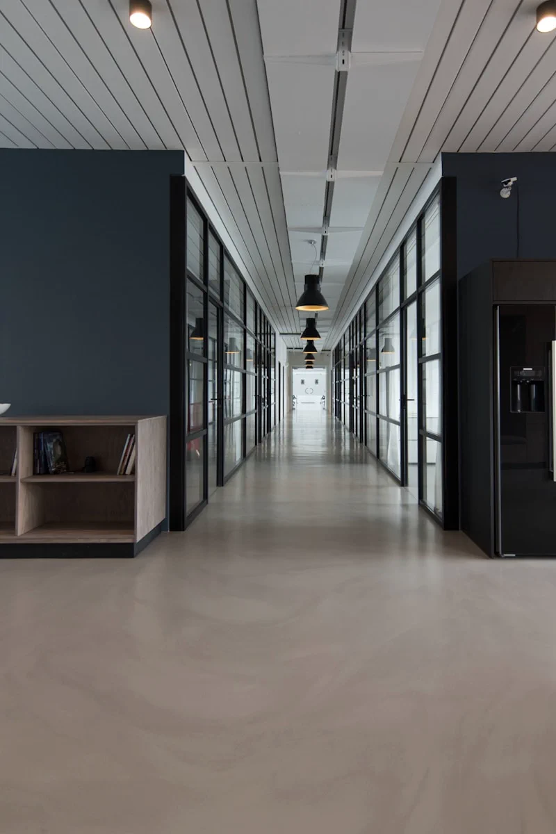 Modern office corridor with glass-walled meeting rooms demonstrating professional workspace